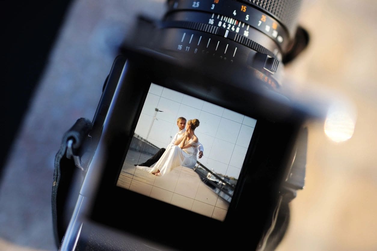 View through a dslr camera screen displaying a bride and groom posing for a wedding photo.